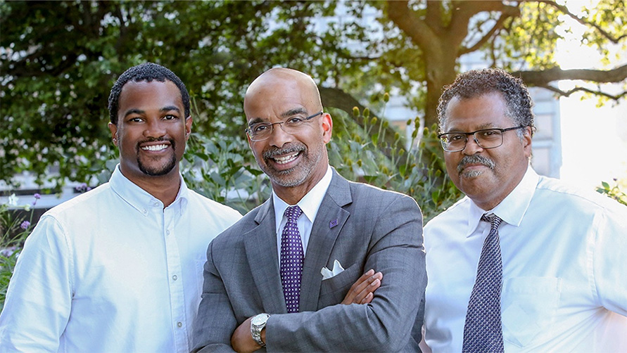 Three men in professional attire pose